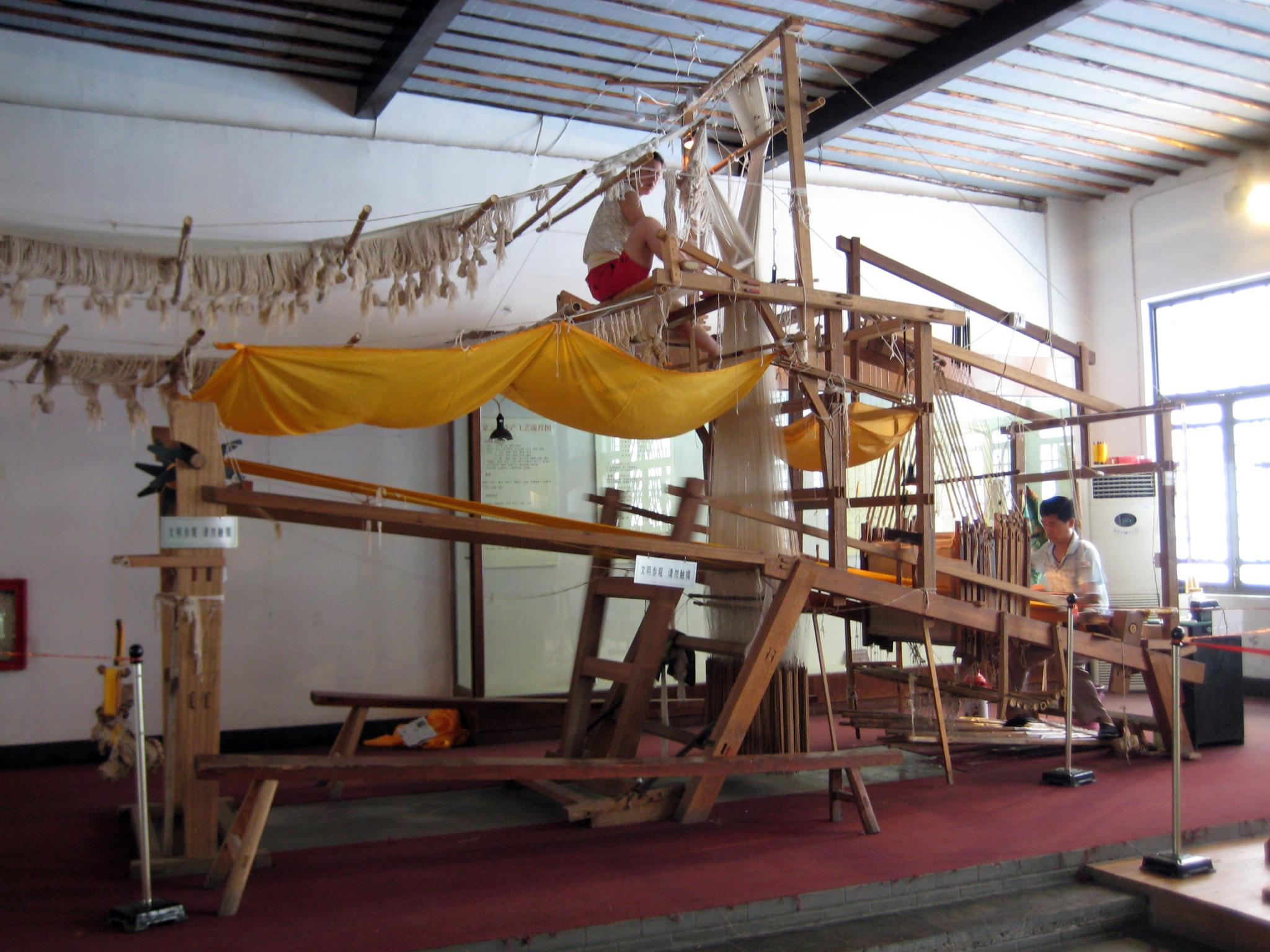 Two people working at a large brocade loom, archival photograph